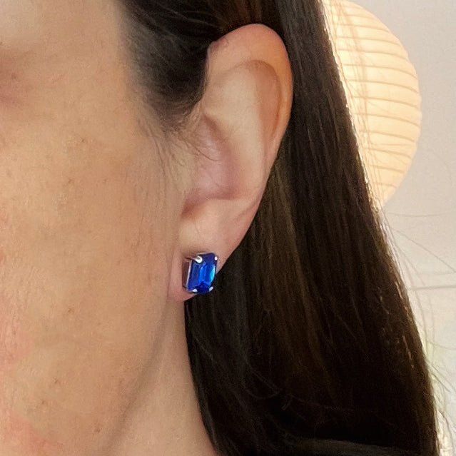 Close-up of an ear wearing a blue earring with a blurred background